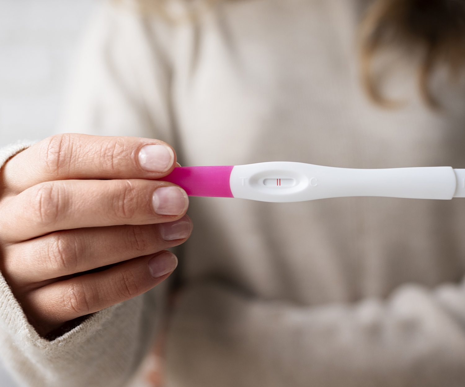 Woman holding a positive pregnancy test showing two lines, symbolising early pregnancy and the first weeks of foetal development.