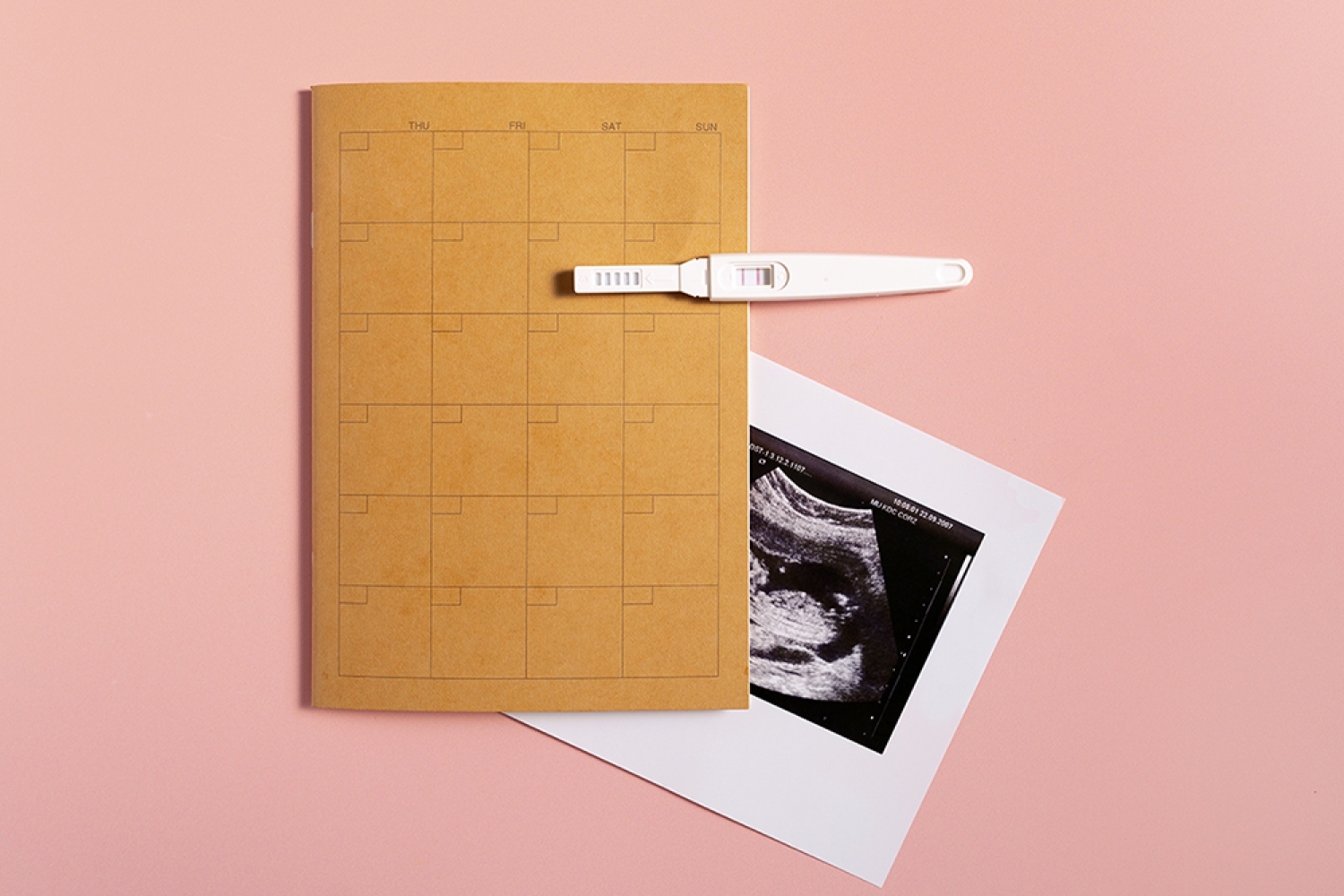 Calendar with pregnancy test and ultrasound scan photo showing early pregnancy preparation