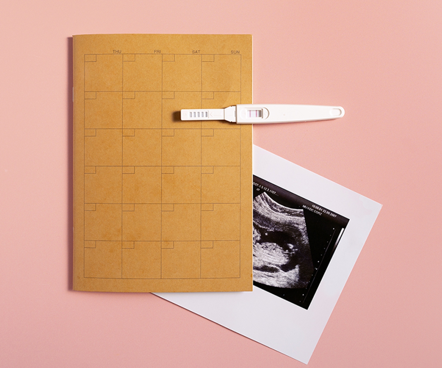 Calendar with pregnancy test and ultrasound scan photo showing early pregnancy preparation