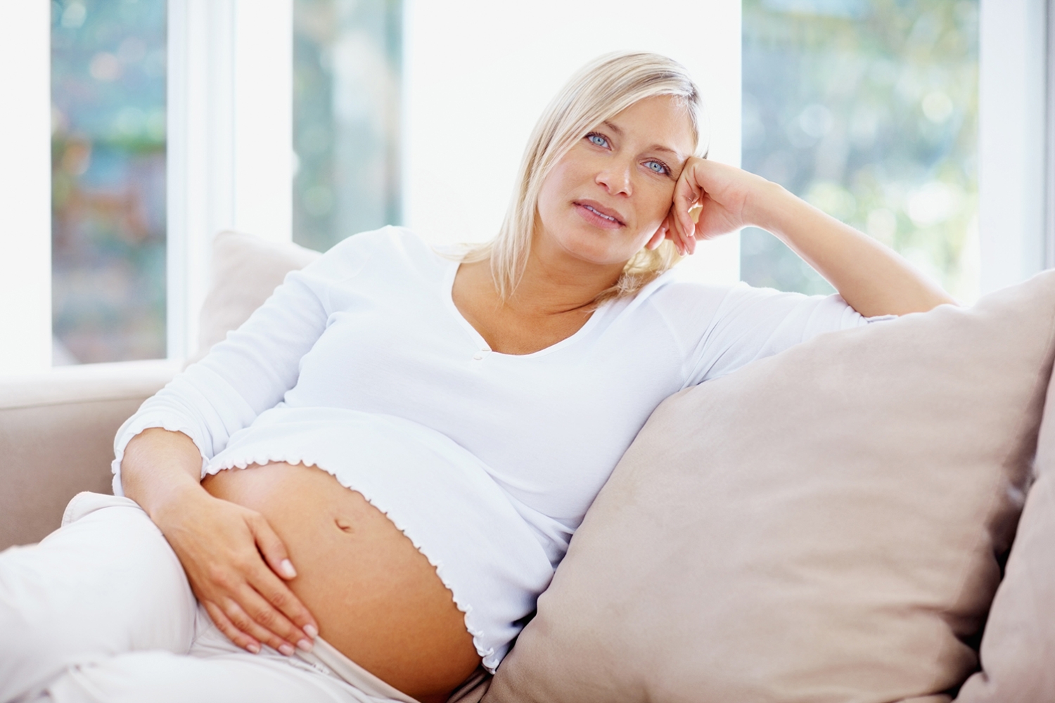 Pregnant woman resting on a sofa with her hand on her bump