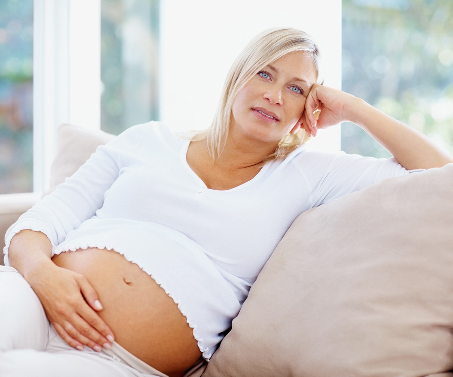 Pregnant woman resting on a sofa with her hand on her bump